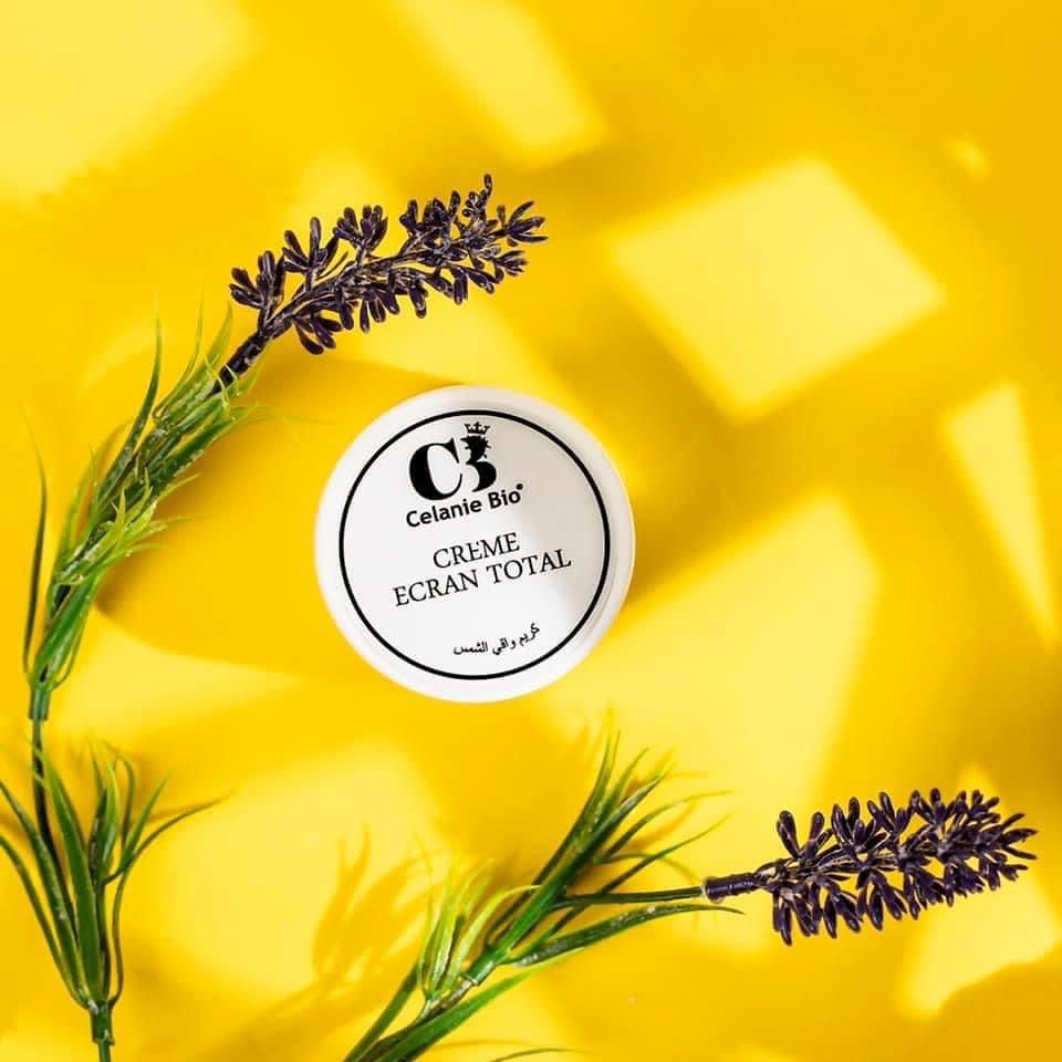Tube de crème solaire bio posé sur du sable avec des ingrédients naturels comme l’aloe vera, l’huile de coco et le beurre de karité, évoquant une protection solaire douce et naturelle.